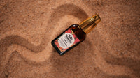 A bottle of Dew of Dunhuang Hydrating Serum placed on a textured sandy background.