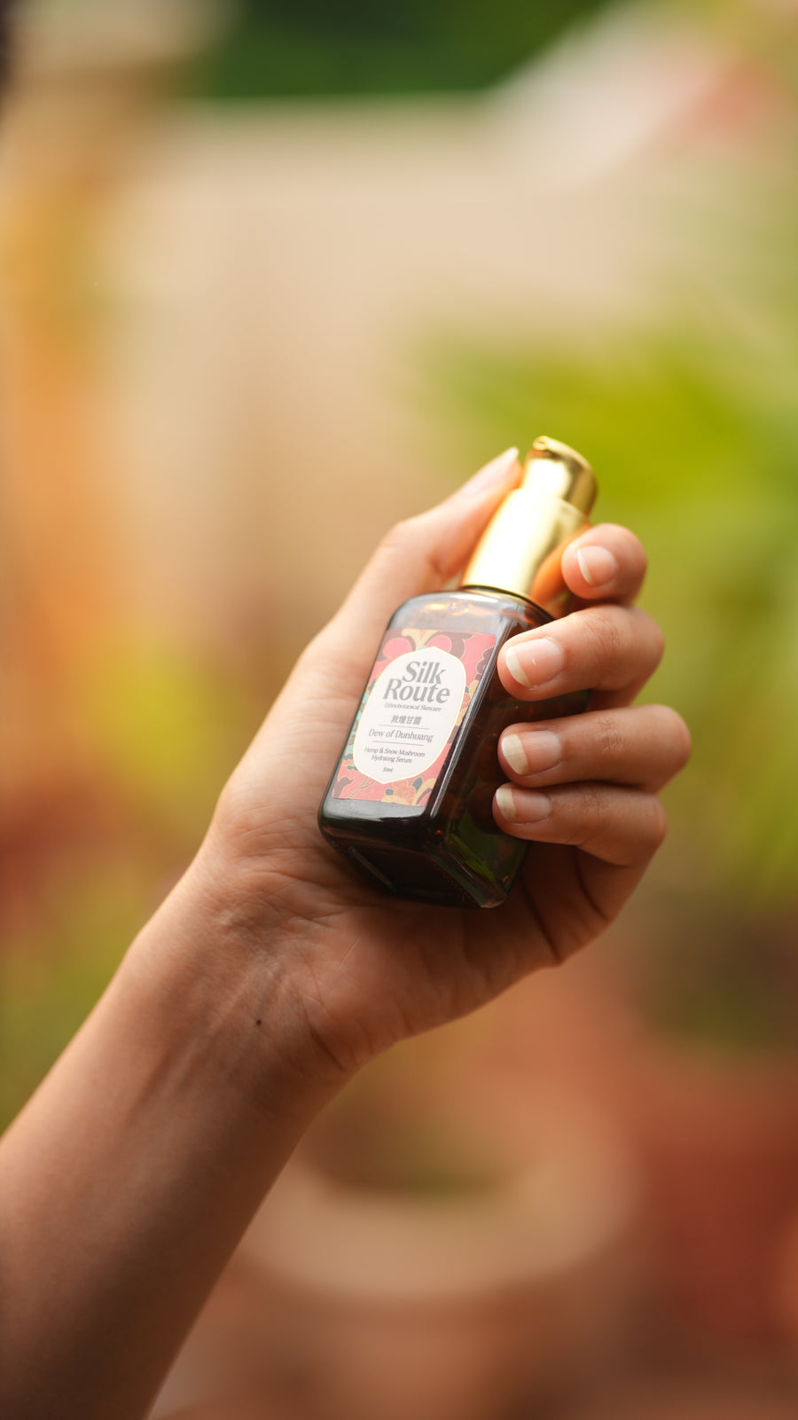 A hand holding the Dew of Dunhuang in a sunlit Bengaluru garden