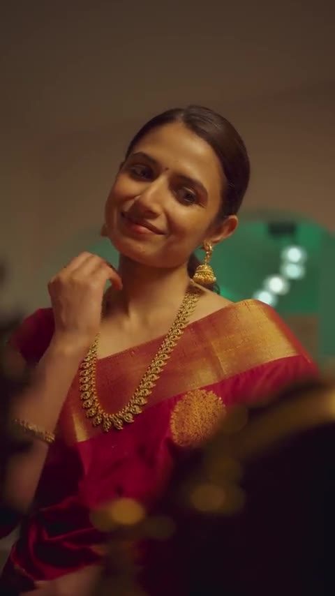 A woman in a red silk saree lit by a brass lamp